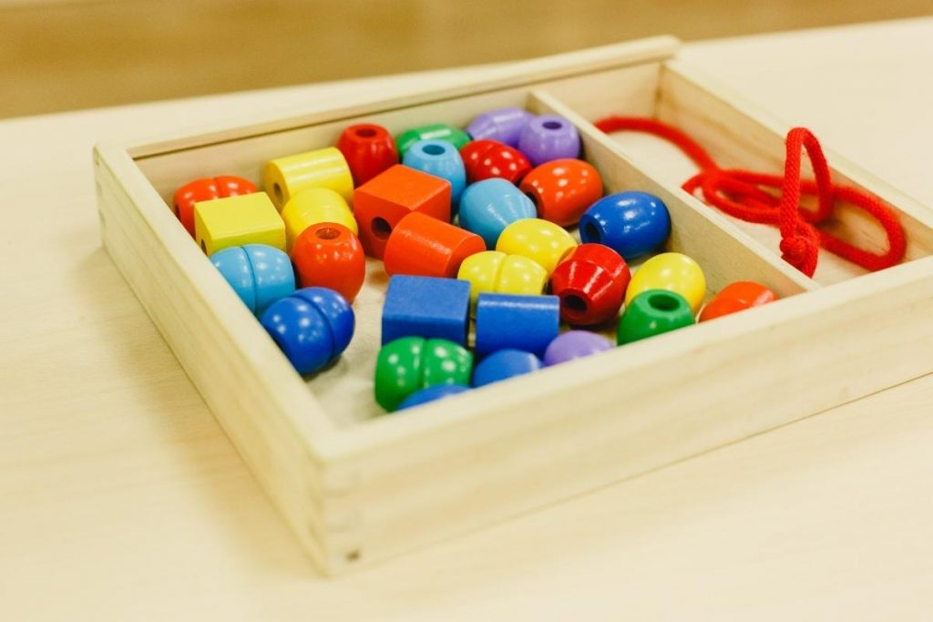 Activité Montessori 3 - 6 ans. Enfiler des perles de couleur en bois sur un fil ou cordon. Reproduire des algorithmes.